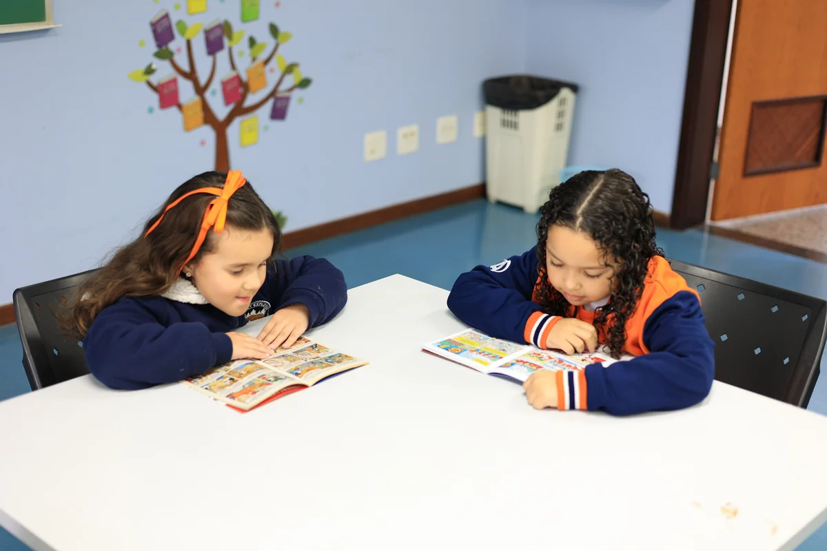 Crianças lendo juntas em mesa da Educação Infantil do Colégio Acesso